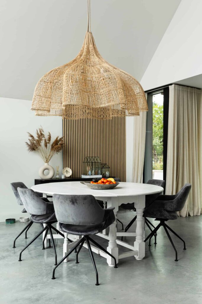 Eetkamer in Nuenen met een gevlinderde betonvloer van Willem Designvloeren. Hierop staat een witte eettafel met daaraan grijze stoelen.