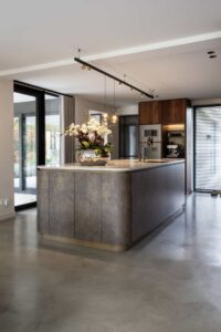 Roestkleurig keukeneiland op een gevlinderde betonvloer in Waalwijk.