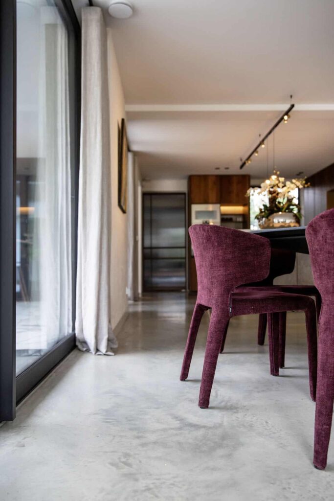 Moderne woning in Waalwijk met een gevlinderde betonvloer. Hierop staan paarse stoelen.