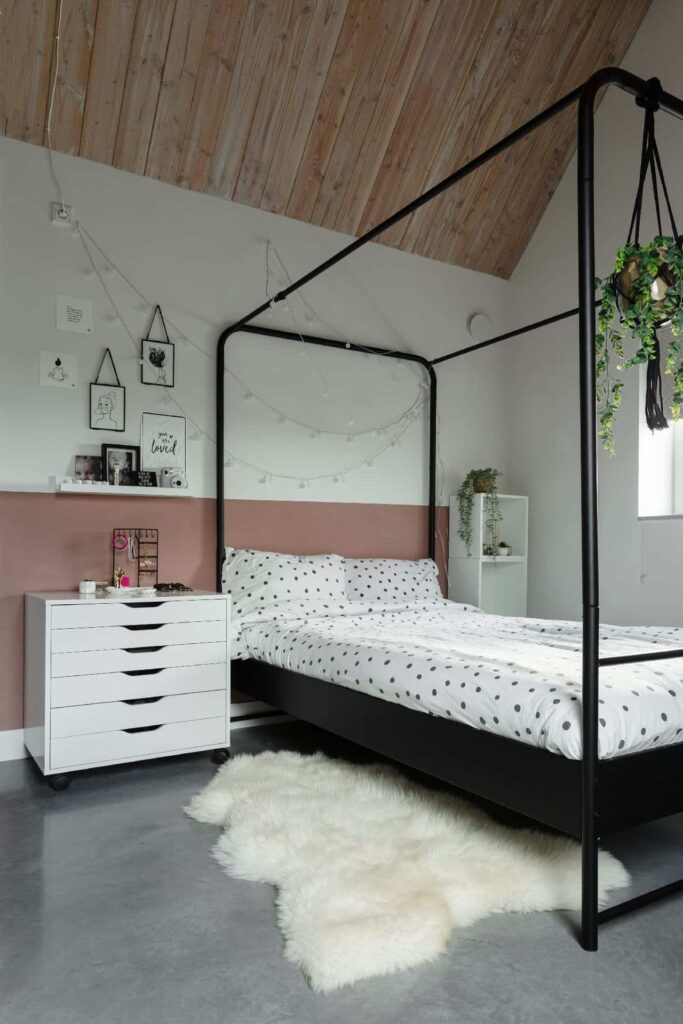 Slaapkamer in Brandwijk. Hierin staat een zwart bed op een gevlinderde betonvloer.