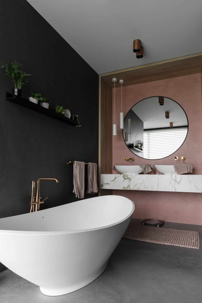 Badkamer met een gevlinderde betonvloer en beton ciré wanden in een antraciete en roze kleur in Bunschoten-Spakenburg.