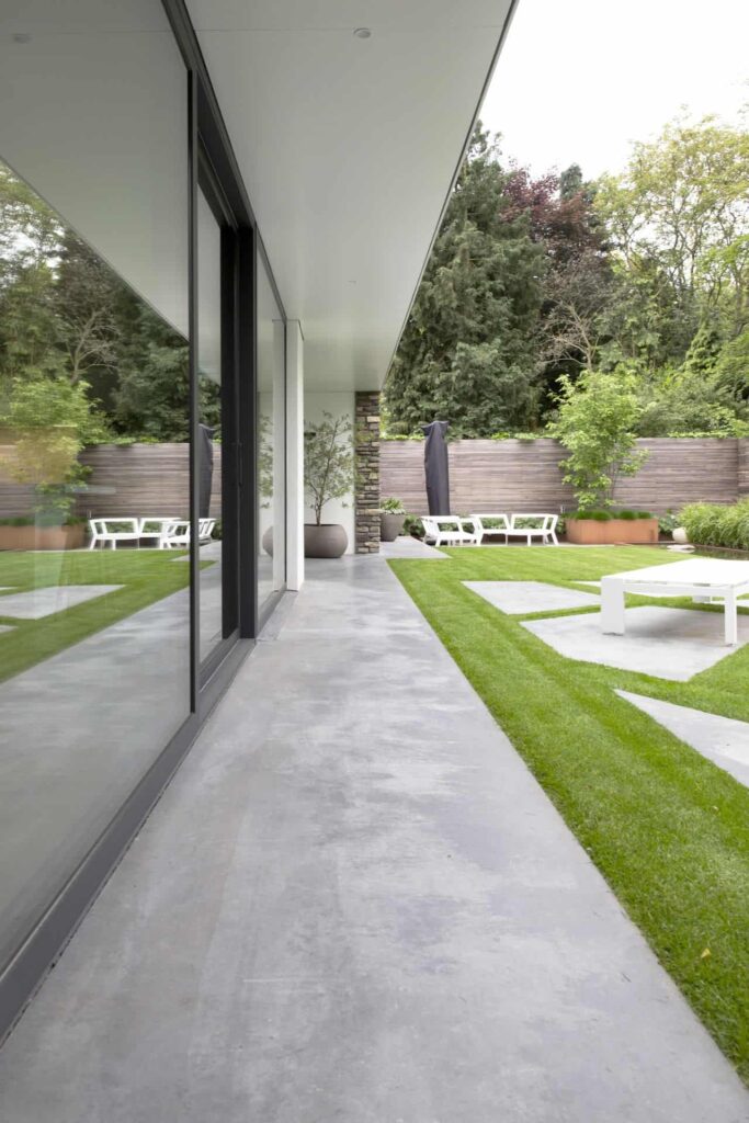 Bungalow in Oisterwijk met een gevlinderd betonnen terras van Willem Designvloeren in een looppad rondom het huis en in vlakken op het terras.