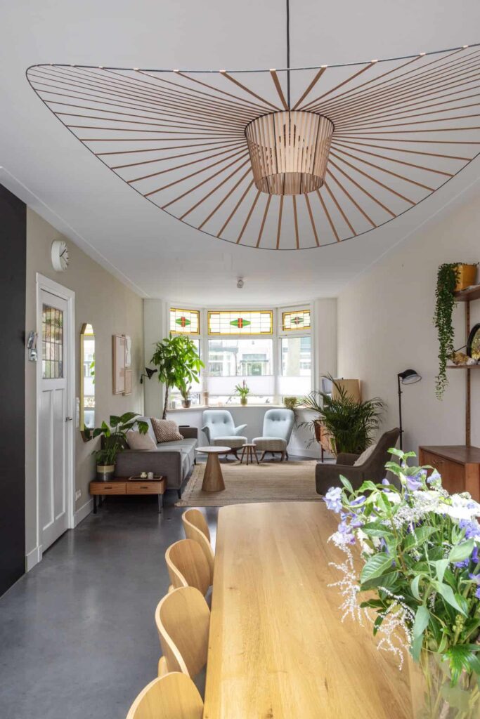 Eet- en woonkamer in Haarlem met houten tafels en een grijze bank. Dit is gecombineerd met een gevlinderde betonvloer