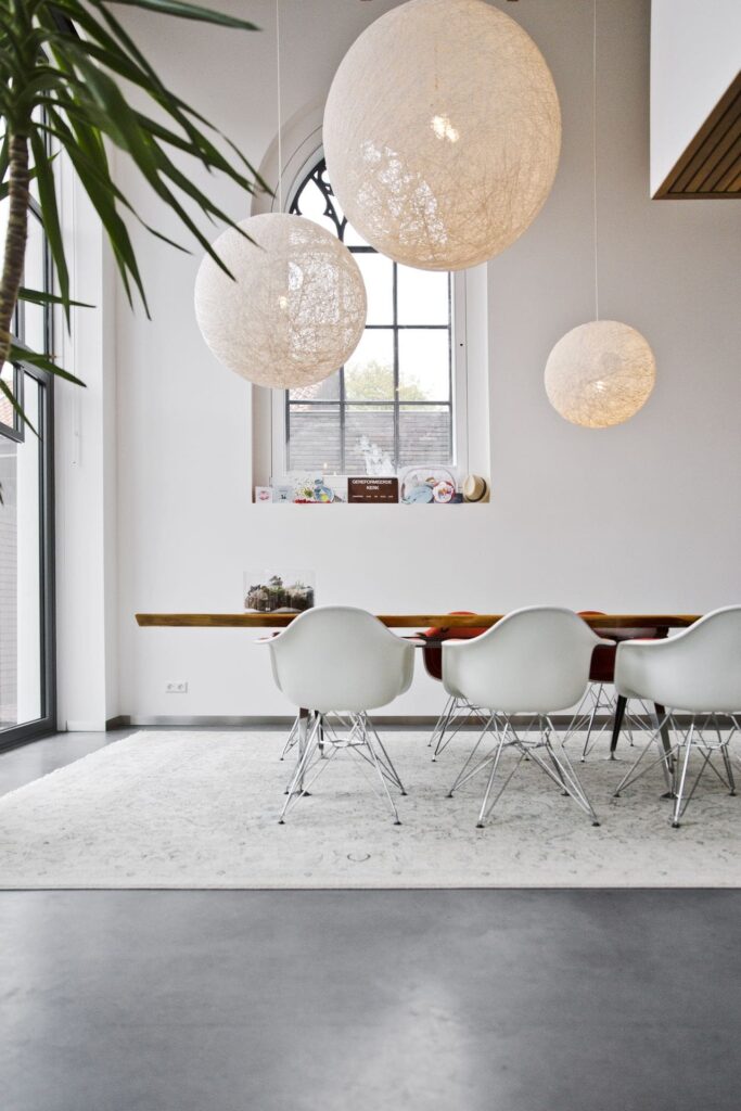 Gevlinderde betonvloer van Willem Designvloeren in de woning in een oud kerkje in Leerdam. Hierop staat een houten tafel met witte stoelen.