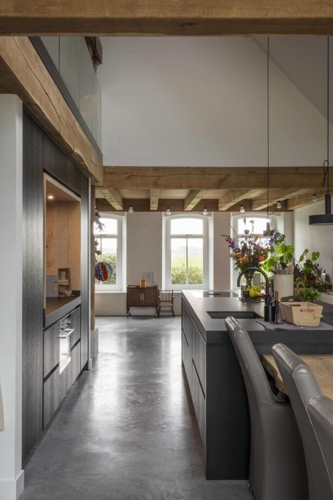 Zwarte keuken in Schagen met een gevlinderde beton vloer in een oude boerderijwoning