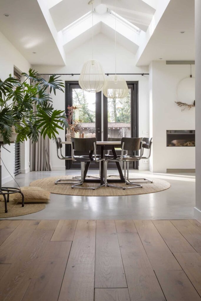 Eetkamer in Lochem met een gevlinderde betonvloer. Gecombineerd met een houten vloer, andere houten details en een grote plant