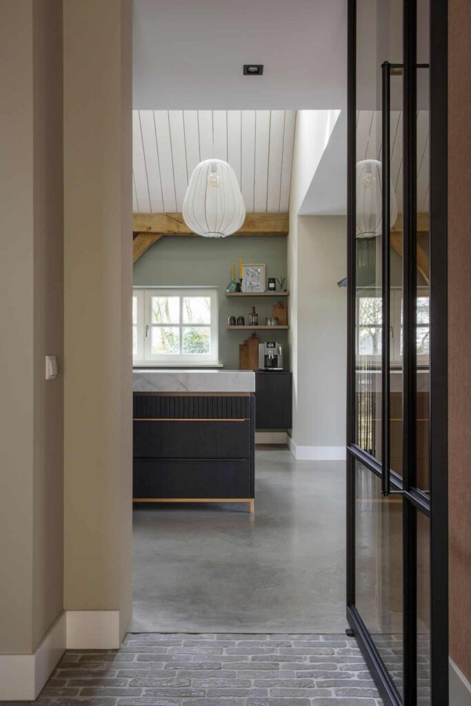 Doorkijkje naar de keuken. Hier staat een zwarte keuken met gouden details en een marmeren blad