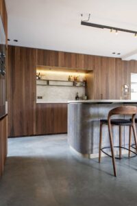 Bruine keukenkasten met een roestkleurig keukeneiland op een gevlinderde betonvloer in Waalwijk.