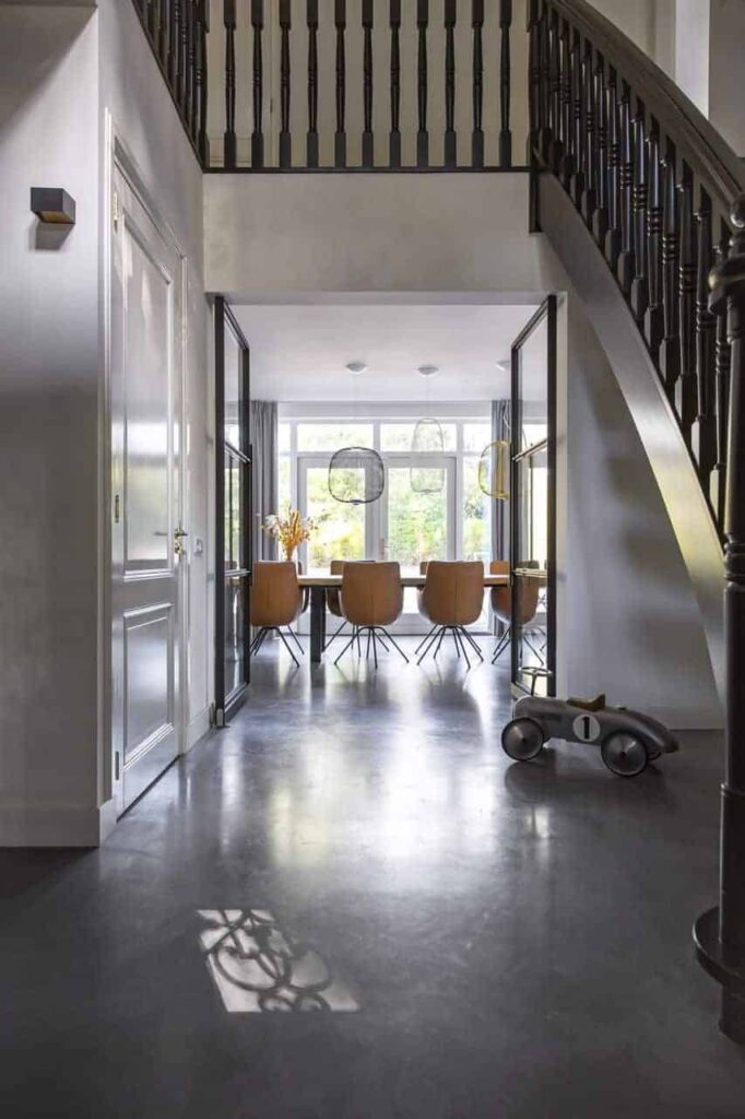 Gevlinderde betonvloer in entree met zwarte klassieke trap 1