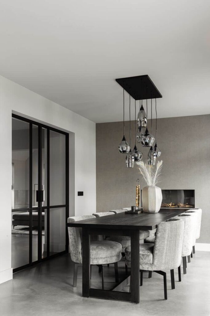 Italiaanse betonlook vloer in Opheusden met daarop een zwarte tafel en daaraan grijze stoelen