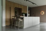 Houten keuken met een wit kookeiland en daaraan beige barkrukken op een gevlinderde betonvloer in Veenendaal.